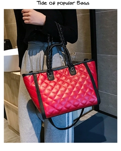 Détail du sac cabas matelassé rouge avec poignées noires et doubles chaînes