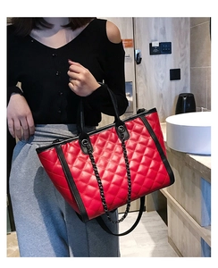 Détail du sac rouge matelassé à losanges avec bordure noire et chaîne métallique