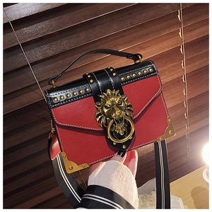 Detail der roten Umhängetasche mit goldener Löwenkopf-Schnalle und dekorativen Nieten