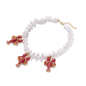 Detailed close-up of baroque pearl necklace with three red lobster pendants and gold clasp