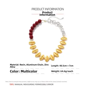 Detail of red beads and silver chain necklace with matte gold lip-shaped charms