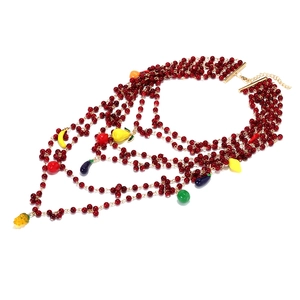 Close-up of bohemian layered red bead necklace with colorful fruit and vegetable charms