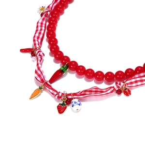 Beaded layered necklace with strawberry, chili and ladybug charms on a white background