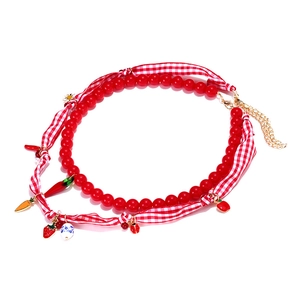 Detail of beaded necklace with strawberry chili pendants and red checkered ribbon