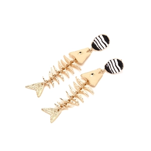 Close-up of gold fishbone drop earrings with black and white striped enamel details