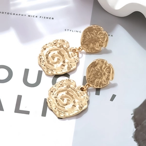 Vue détaillée de boucles d'oreilles dorées avec texture martelée et forme florale d'art