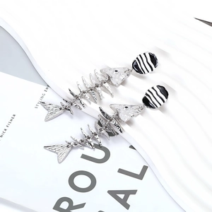 Close-up of flexible fishbone earrings with textured silver alloy and enamel details