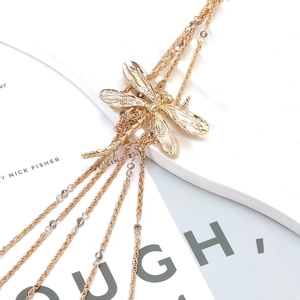 Detail of dragonfly pendant necklace with golden fringe tassels and grey faceted beads