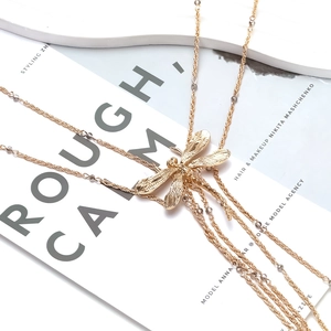 Retro dragonfly layered gold chain necklace with beads on white marble and magazine