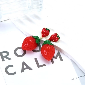 Boucles d'oreilles fraise rouge avec feuilles vertes sur carte décorative blanche