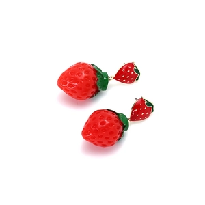 Vue macro de boucles d'oreilles fraises en émail 3D avec détails de feuilles vertes