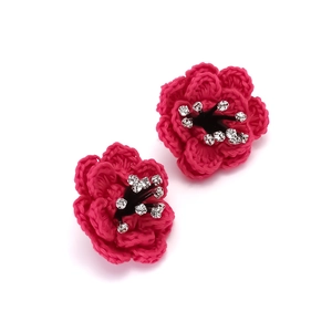 Macro view of handmade layered red camellia earrings with sparkling rhinestone center