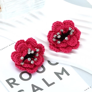 Close-up of handmade red woven camellia earrings with sparkling rhinestone centers