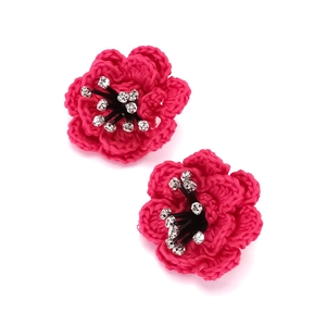 Macro detail of hand-woven layered camellia earrings with rhinestone center and knit texture