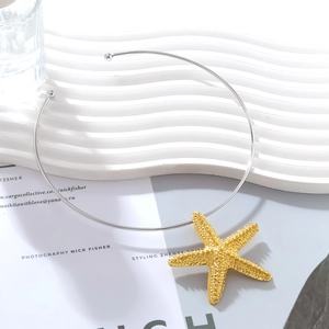 Detail of golden starfish pendant on silver neck collar with textured grain finish