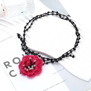 Detail of red crochet camellia flower pendant on multi-layer black beaded necklace