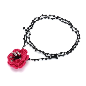 Macro detail of hand-crocheted pink camellia flower necklace with rhinestone and black beads