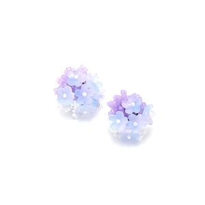 Macro shot of handmade beaded flower earrings featuring light blue and purple petals