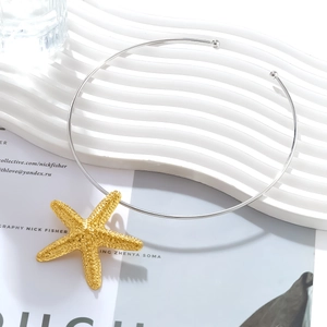 Minimalist silver choker with detailed gold starfish pendant on white textured background