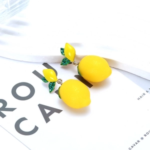 Fresh lemon drop earrings with green crystal leaves on a minimalist white stone base