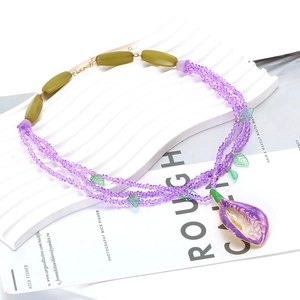Detail of multilayer purple crystal beads with green leaves and flower pendant necklace
