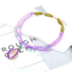 Multilayer purple beaded necklace with green leaf accents and artistic floral pendant