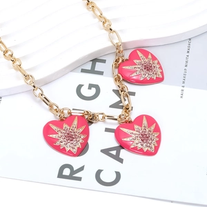 Details einer Goldkette mit rosa Emaille-Herzanhängern und funkelnden Sternen-Kristallen