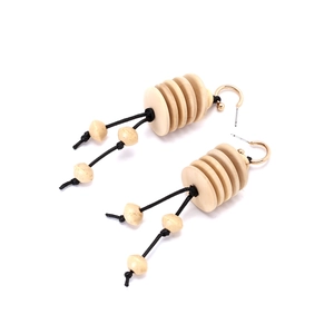 Detail of bohemian handmade wooden bead earrings with woven tassels and gold metal hooks