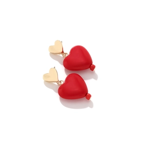 Macro detail of red resin heart pendant earrings with matte finish and gold metallic studs
