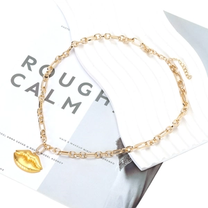 Close-up of gold chunky chain necklace with textured lip pendant and lobster clasp