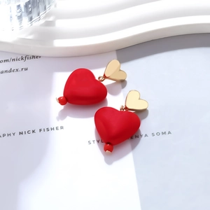 Detail of red matte resin heart earrings with gold stud on aesthetic background