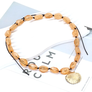 Chunky amber jelly bead necklace with a gold alloy shell pendant on a display stand