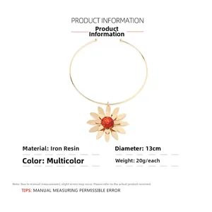 Detail of 13cm diameter gold metal choker with a red and gold resin daisy pendant
