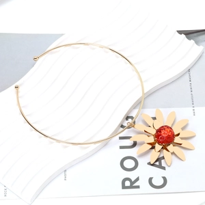 Golden collar necklace featuring a large sunflower pendant with a textured red bead center