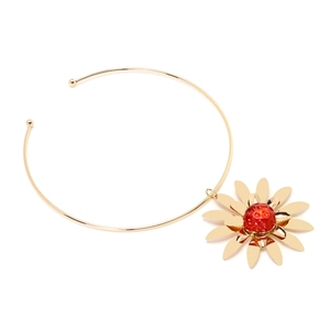 Detail of a large gold floral pendant choker featuring a textured red berry-like center