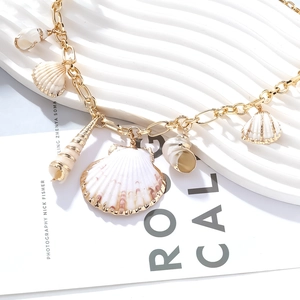 Vue détaillée des pendentifs coquillages dorés d'un collier fait main unique