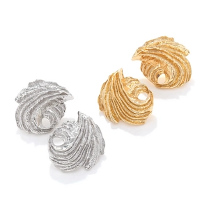 Macro detail of textured gold and silver leaf earrings with hammered metal surface