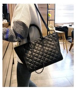 Détail d'un grand sac cabas noir avec matelassage en losanges et lanières en chaîne