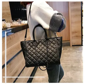 Mannequin portant un sac cabas matelassé noir avec bandoulière chaîne en intérieur