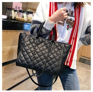 Détail du sac cabas matelassé noir avec bandoulière chaîne porté par le mannequin