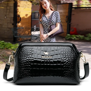 Detail of black faux crocodile leather bag with gold kangaroo logo and metallic buckles