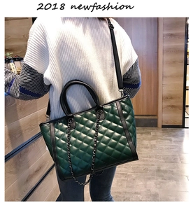 Détail du sac bandoulière matelassé vert foncé avec bordure noire et chaîne en métal
