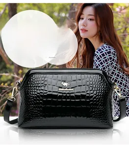 Detail of black faux crocodile leather handbag with golden kangaroo logo and glossy finish