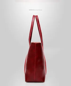 Vue latérale du sac fourre-tout rouge foncé brillant avec structure trapézoïdale et coutures
