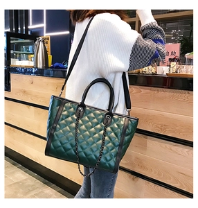 Sac cabas matelassé vert foncé avec chaîne porté dans une scène de rue lifestyle