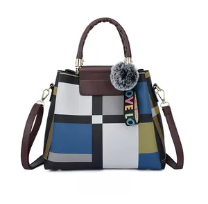 Detail of multi-color patchwork tote bag with plaid patterns and plush ball charm