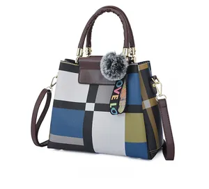 Detail view of multicolored plaid handbag featuring premium leather handles and love charm