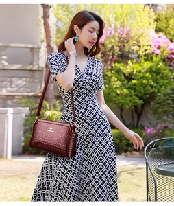Close-up of burgundy patent leather bag with crocodile pattern and golden kangaroo logo