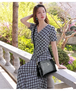 Detail of black faux leather crossbody bag with crocodile texture and golden logo