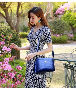 Blue crocodile pattern crossbody bag with golden kangaroo logo and shoulder strap detail